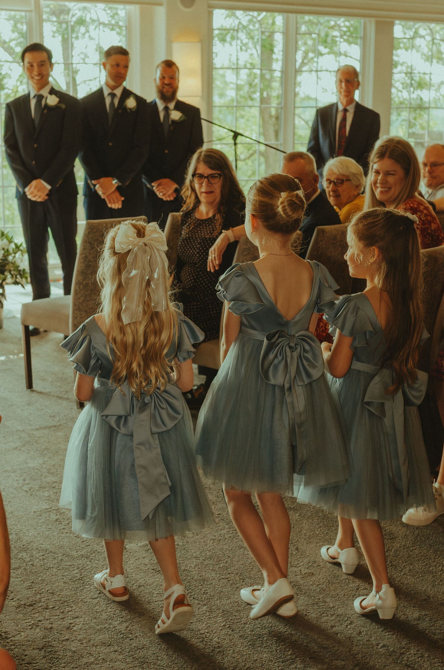 Bridesmaids in dusty blue dresses gather and interact during a wedding celebration.