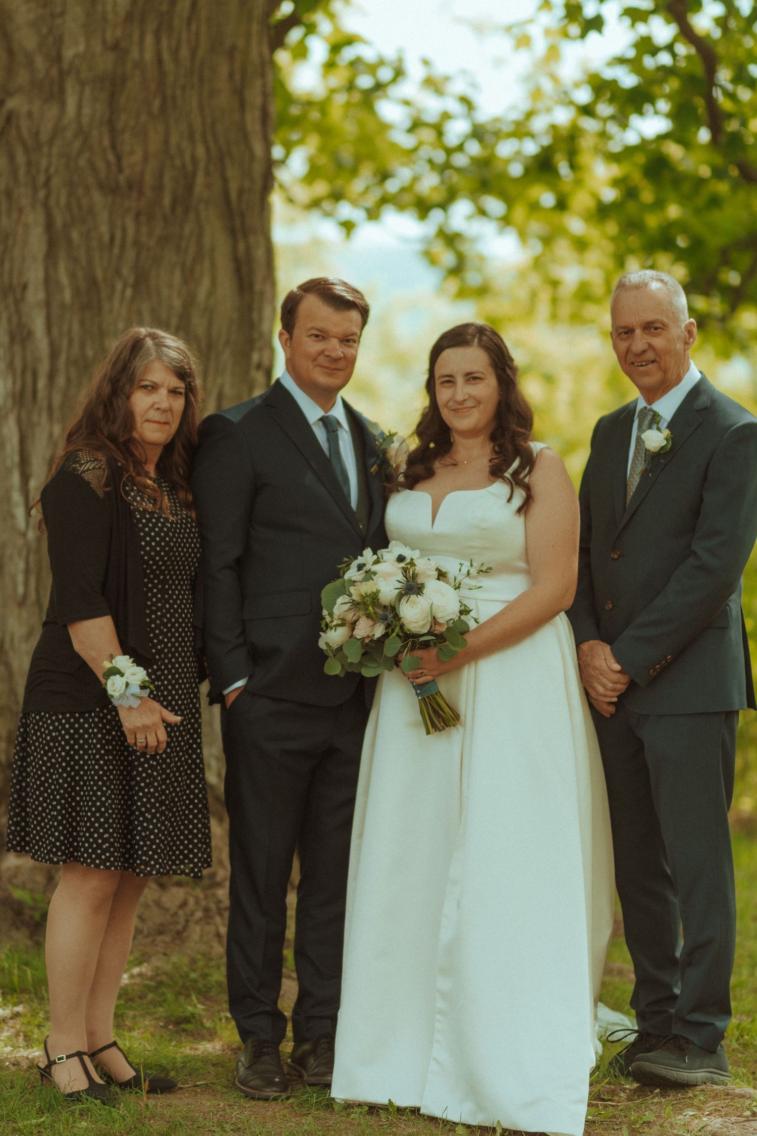 Wedding party members gather for casual portraits in an outdoor garden setting.
