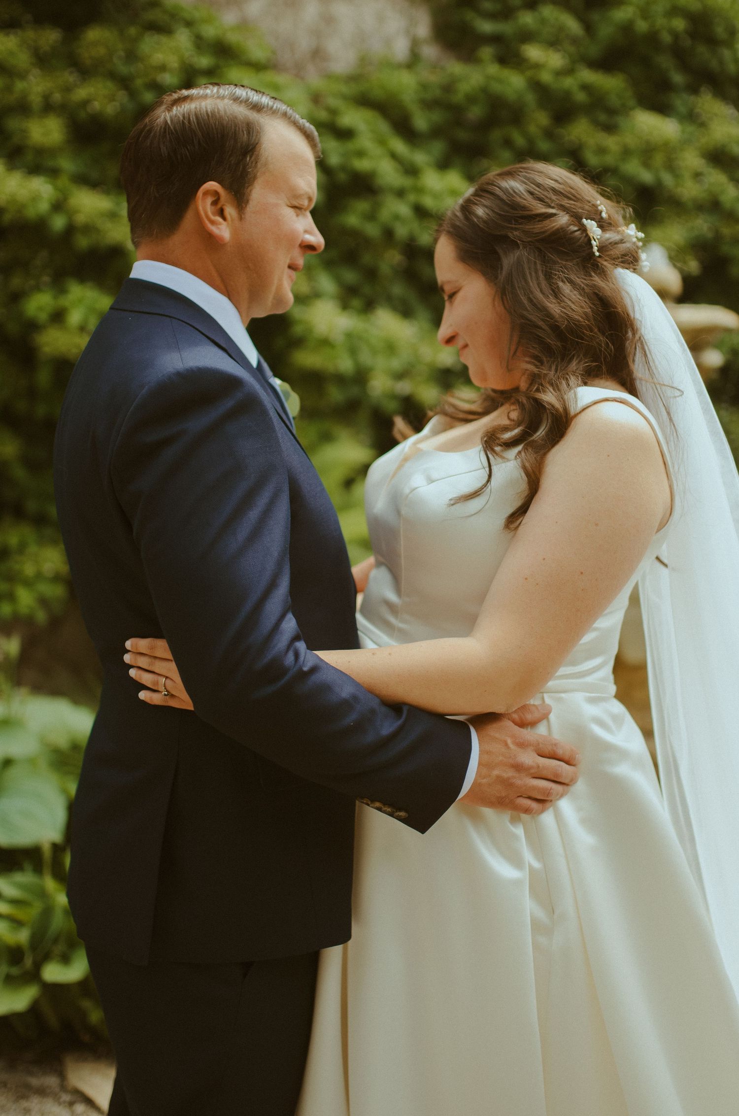 An intimate wedding portrait showing the couple embracing outdoors.