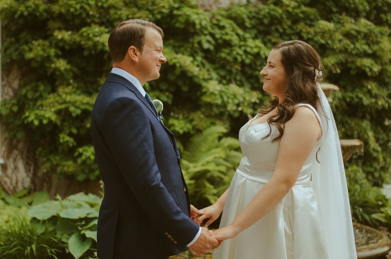 Intimate wedding moment captured in a garden setting with natural sunlight.