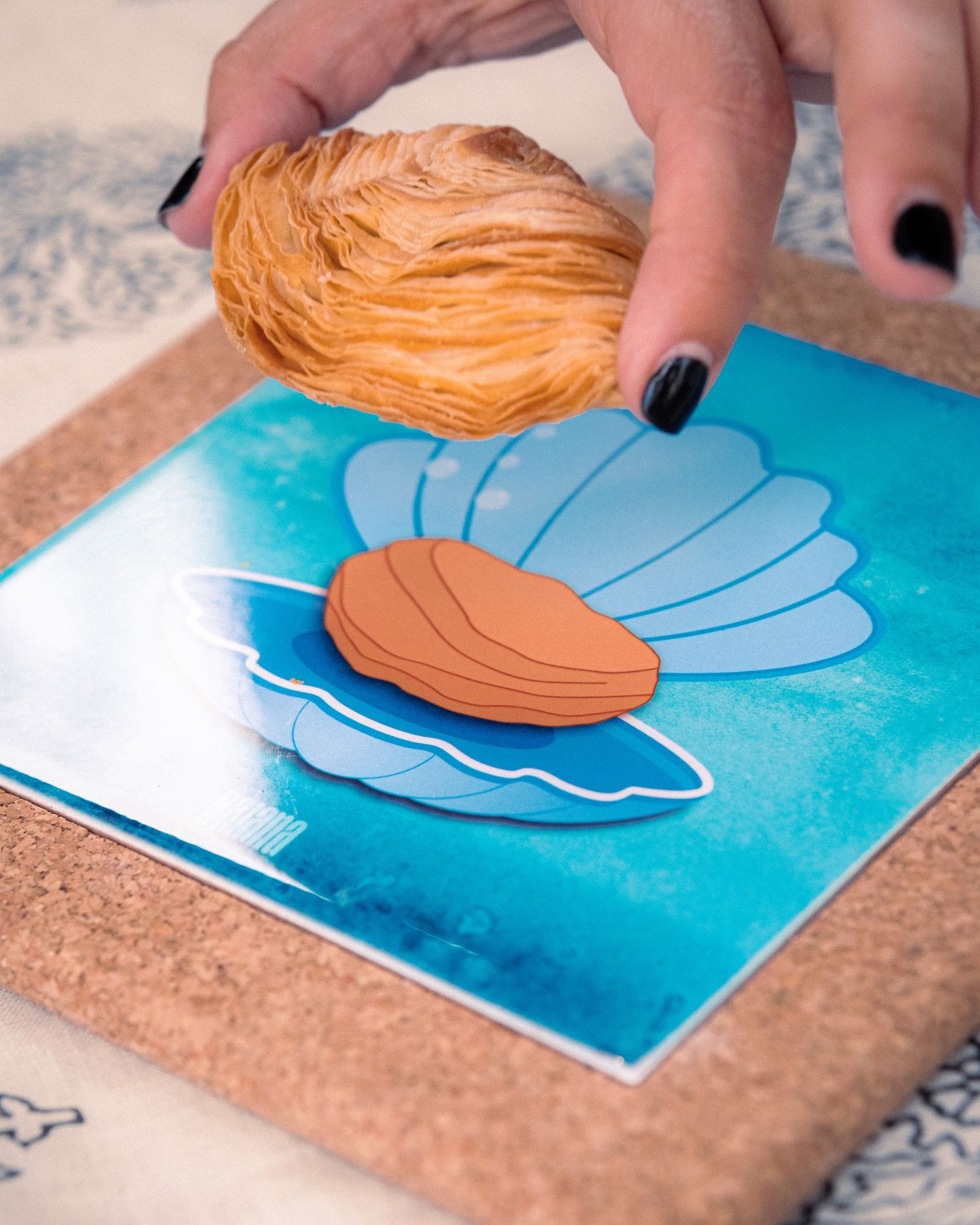 Hands arranging blue and orange paper cutouts on a turquoise background.