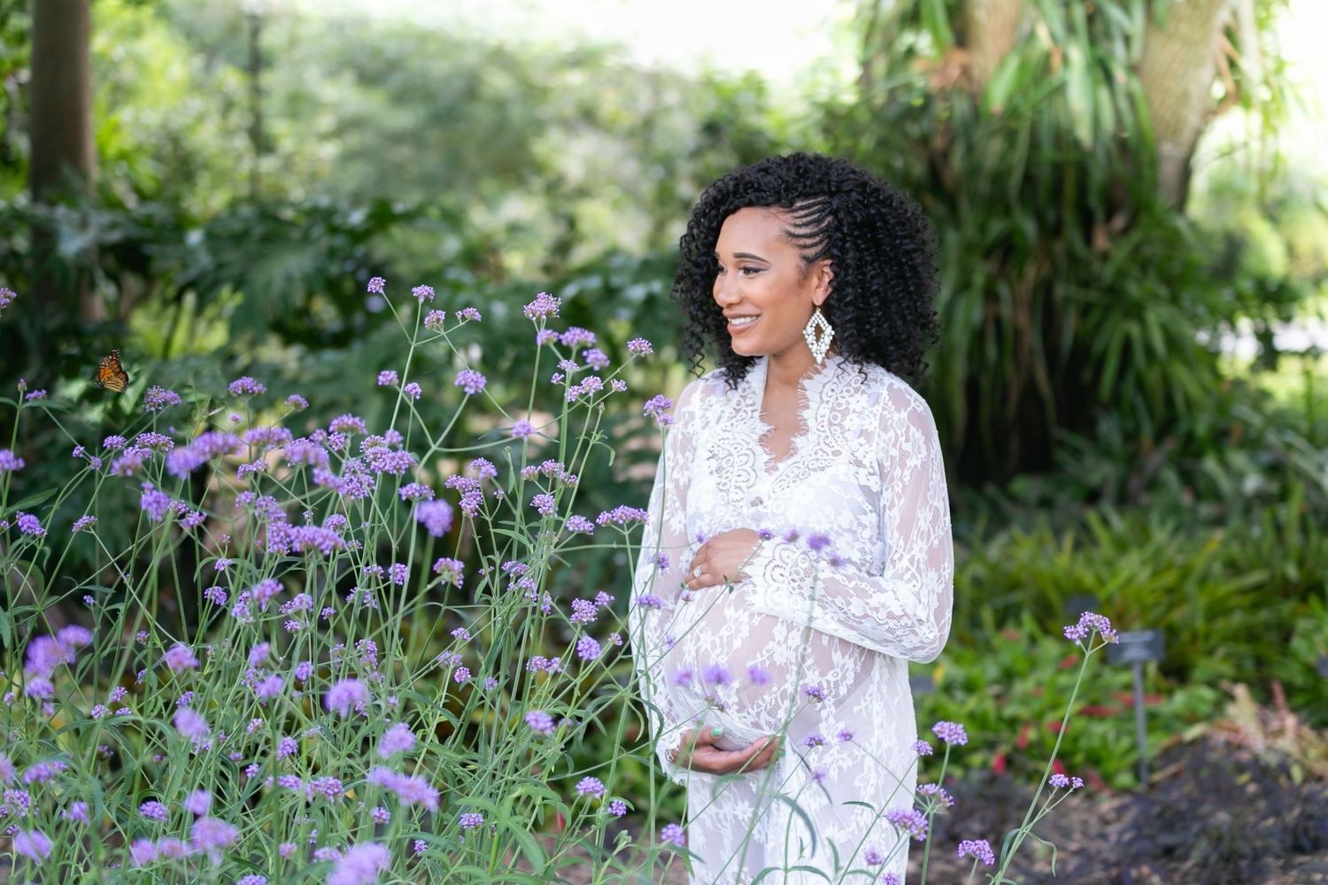 A pregnant woman in a white floral dress poses outdoors at Kraft Azalea Park, Orlando Maternity Photography, Sanford Maternity Photography