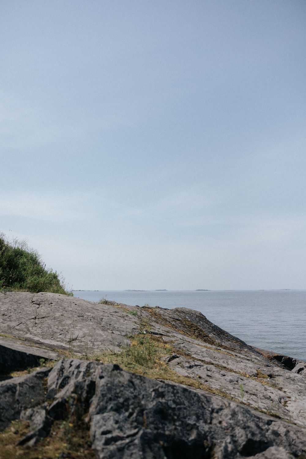 Rocky coastal landscape with views of the ocean and distant hills on a cloudy day.
