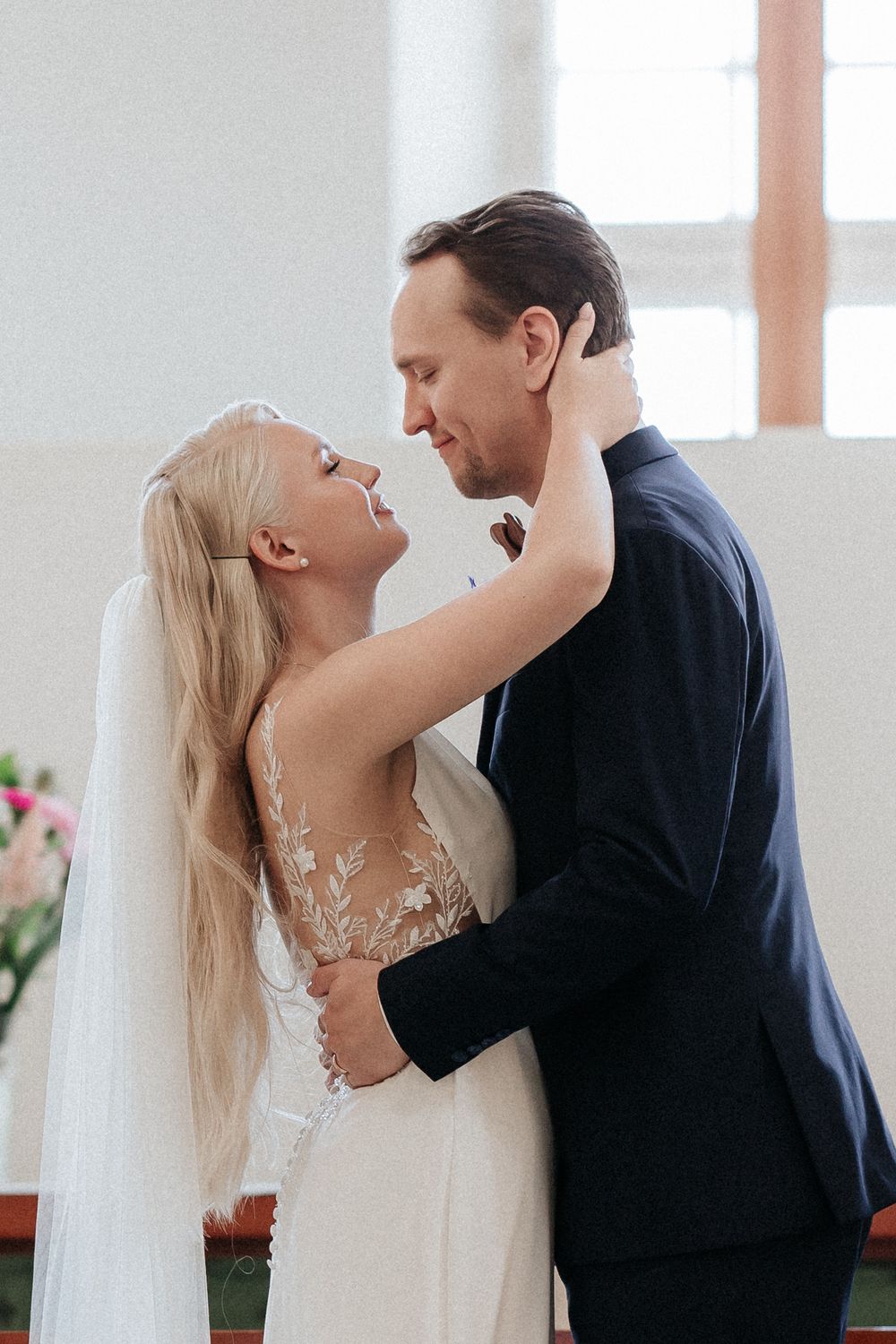 A bride and groom sharing their first kiss in sequence during a wedding ceremony in a bright indoor venue.