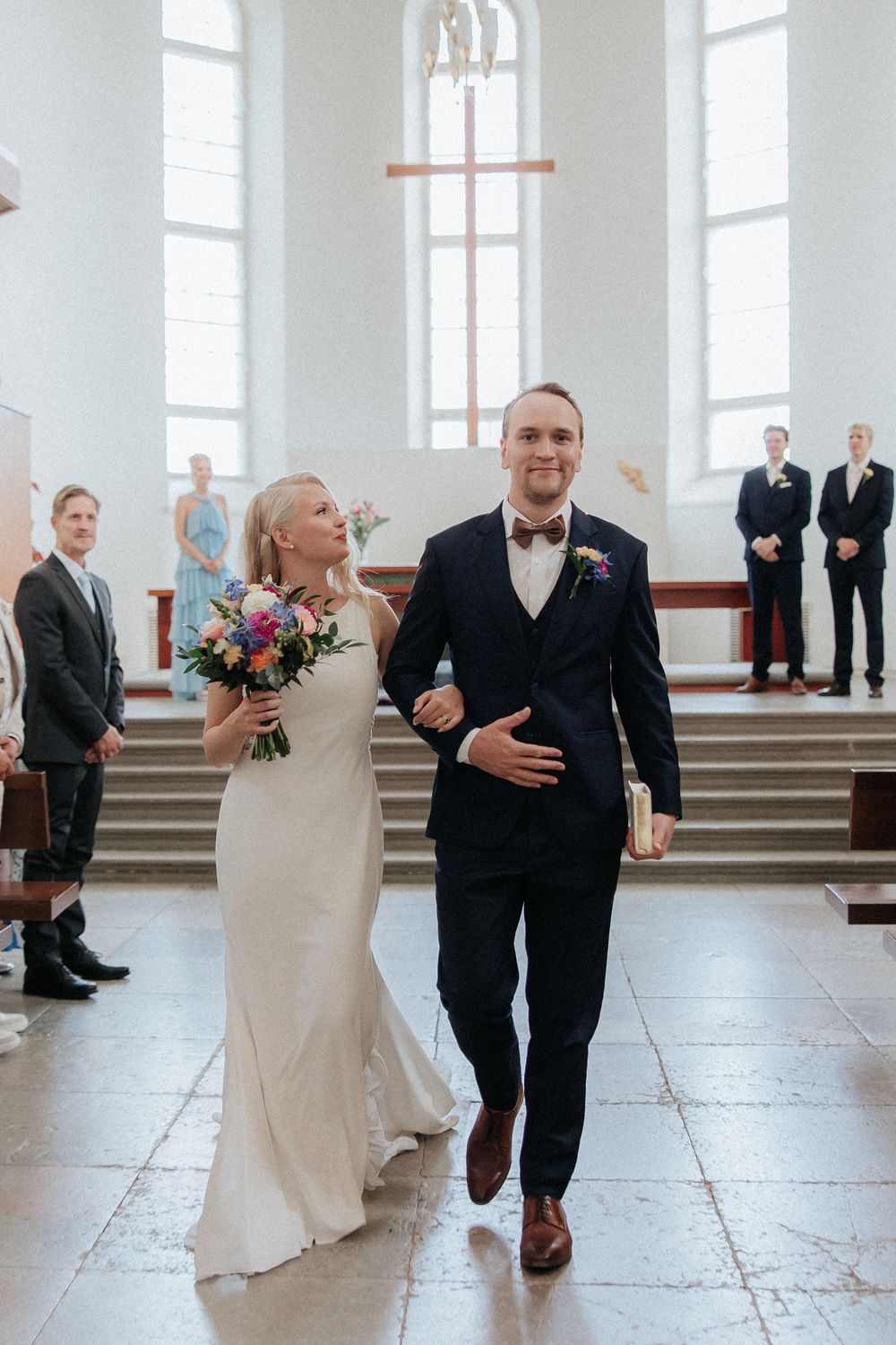 A celebratory recessional sequence showing the newlyweds walking down the church aisle after their ceremony.