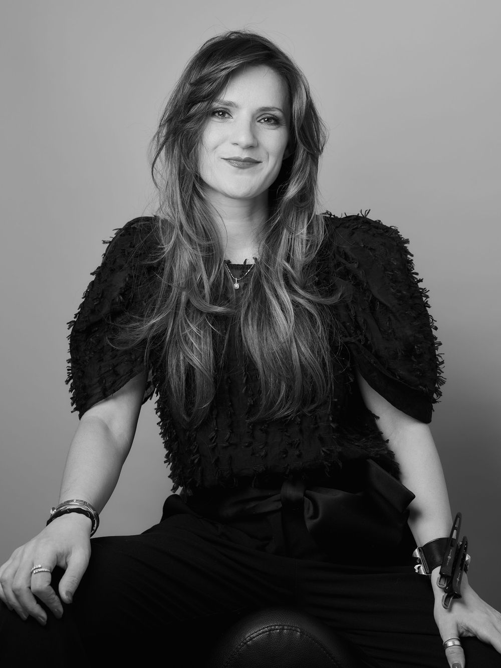 Black and white portrait series showing someone in a textured black top against a light backdrop creating a dramatic contrast.