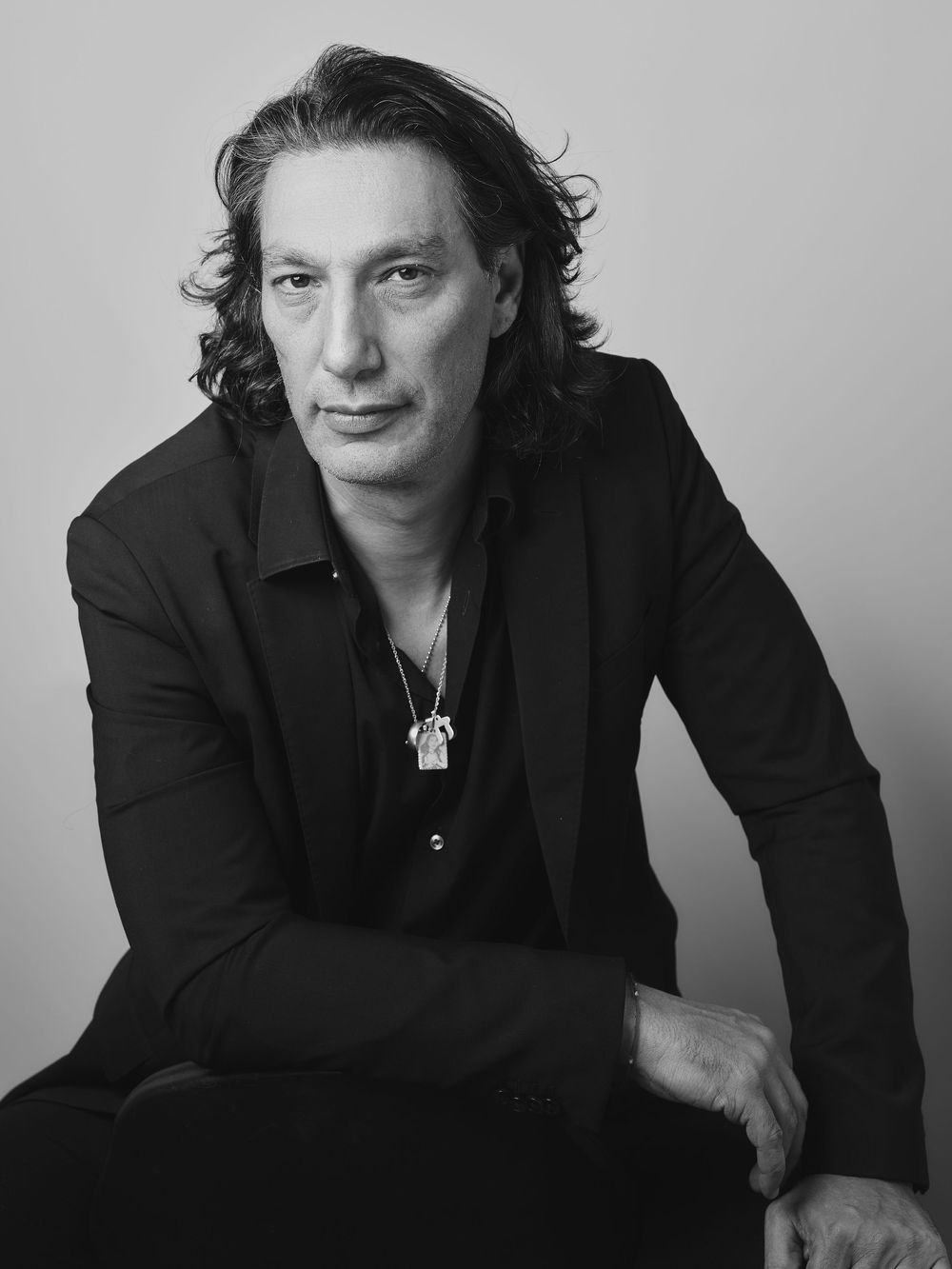 Series of black and white portraits showing a figure in dark attire posing against a simple backdrop.