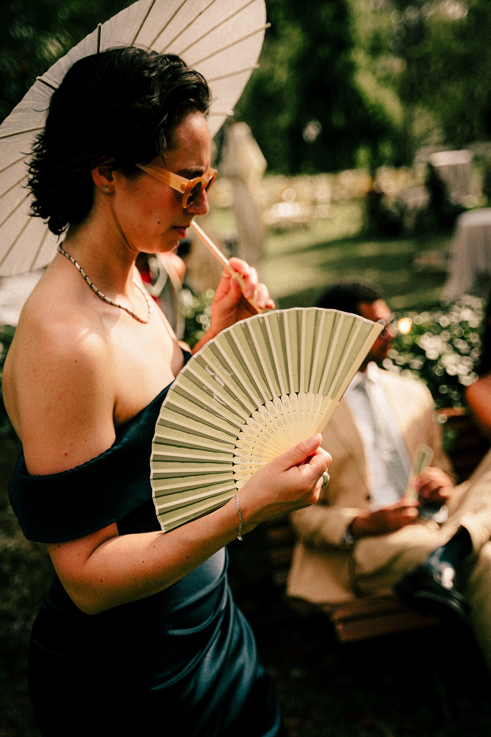 Four sequential photos show a figure in black holding and fanning a cream-colored folding fan in natural outdoor lighting.