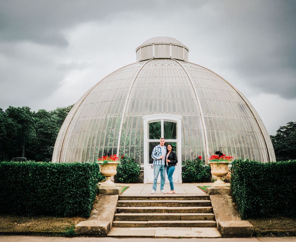 A panoramic collage of a white domed greenhouse structure with stone steps and cloudy sky in the background.