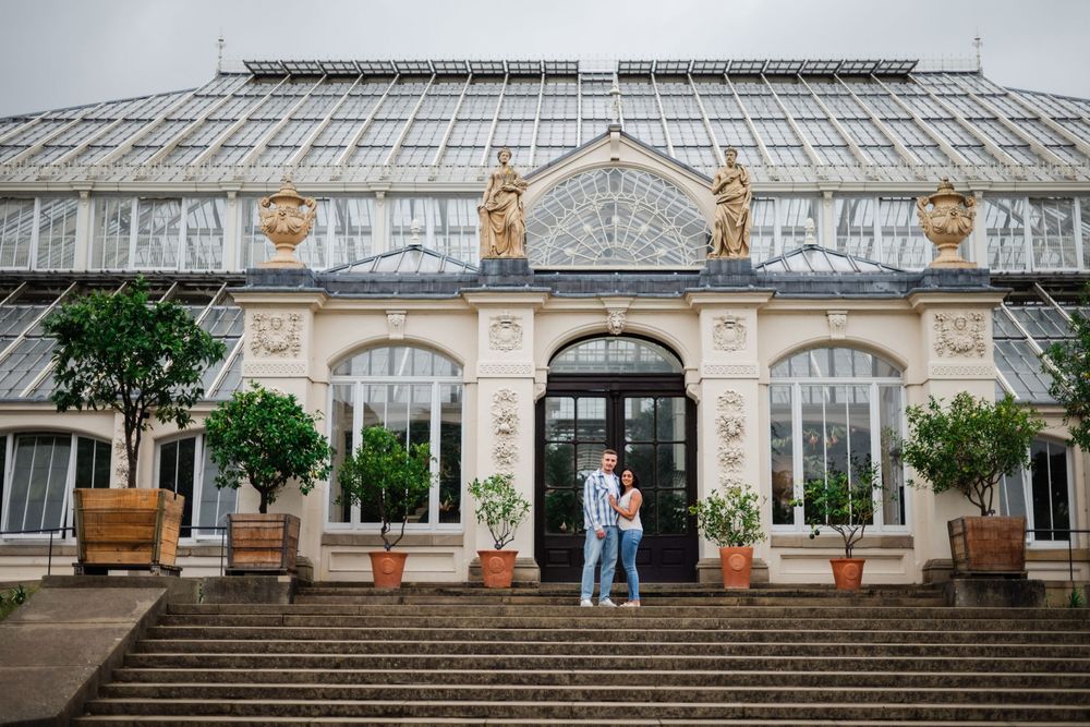 A grand Victorian-style conservatory with ornate architecture and potted plants decorating the entrance.