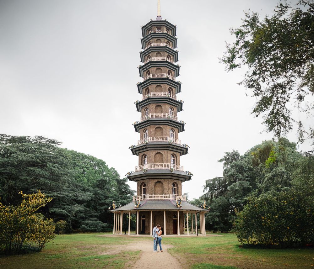 Ornate pagoda tower rises above green trees and gardens at the Kew Royal Botanic Gardens in London.