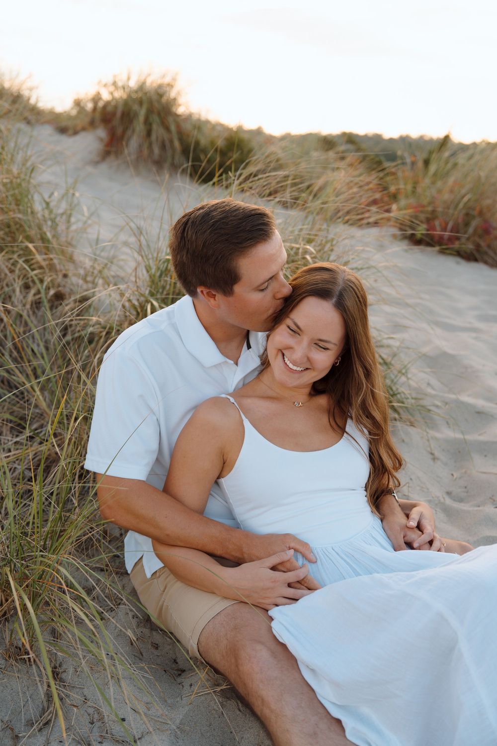 A couple relaxing and embracing on a sandy beach during a romantic photo session.