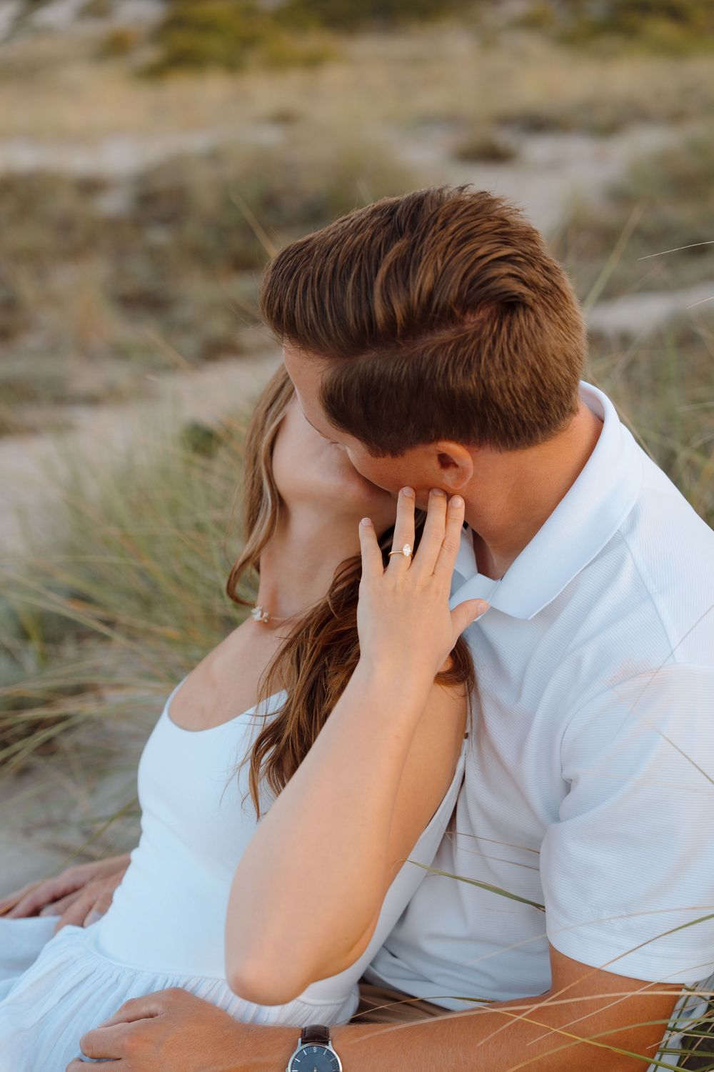 A romantic beach scene shows a couple in white clothes sharing tender moments and kisses by the ocean.