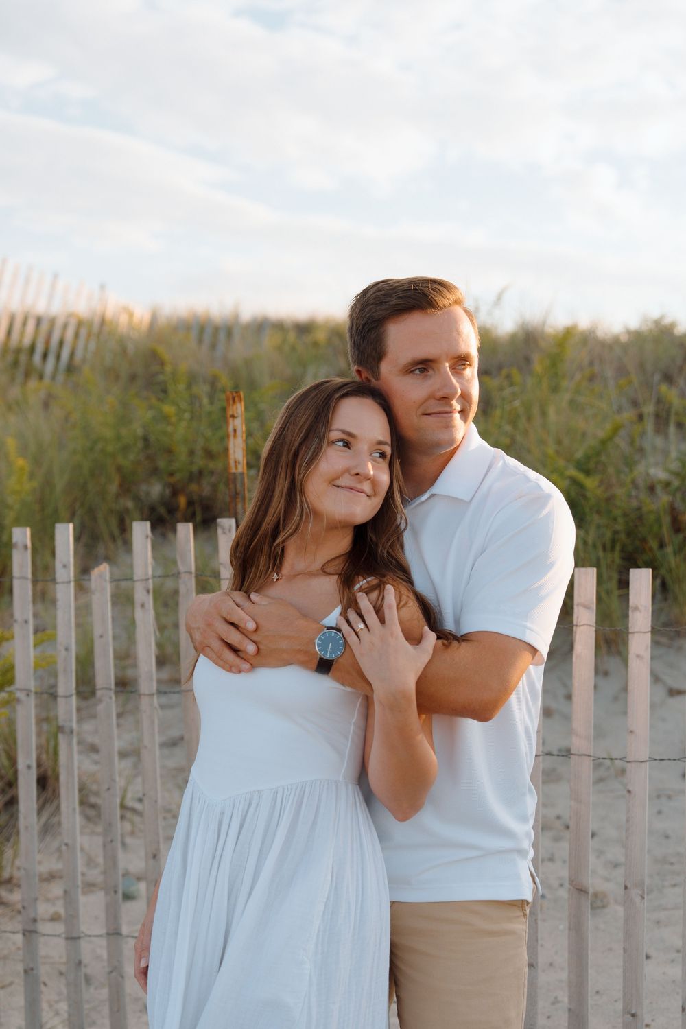 Couple shares tender moments against a backdrop of weathered beach fences during golden hour.