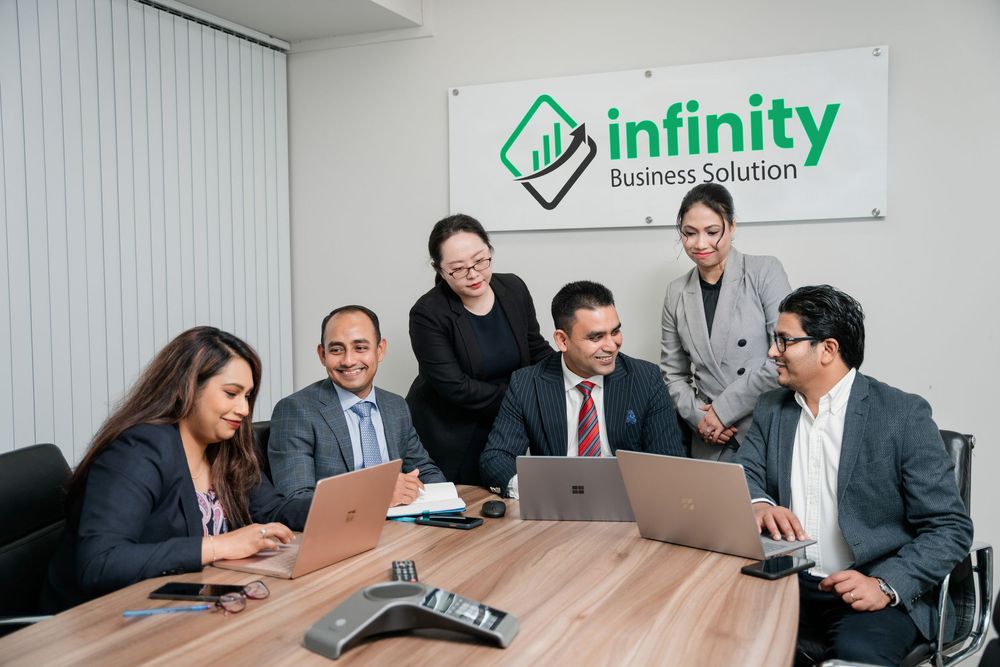 Business professionals collaborating at a modern office conference table with laptops during a meeting.