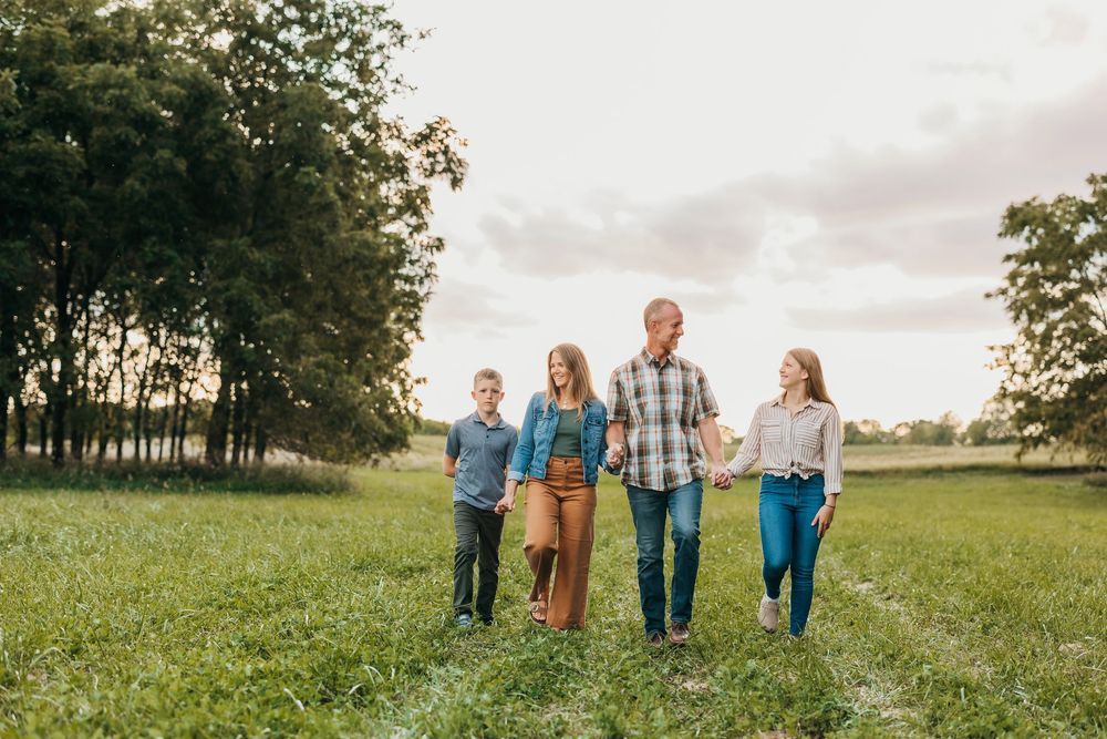 Group walking together in an open grassy meadow during golden hour with trees in the background.