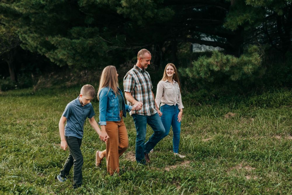 Family plays and runs together in lush green field during golden hour outdoor photo session.