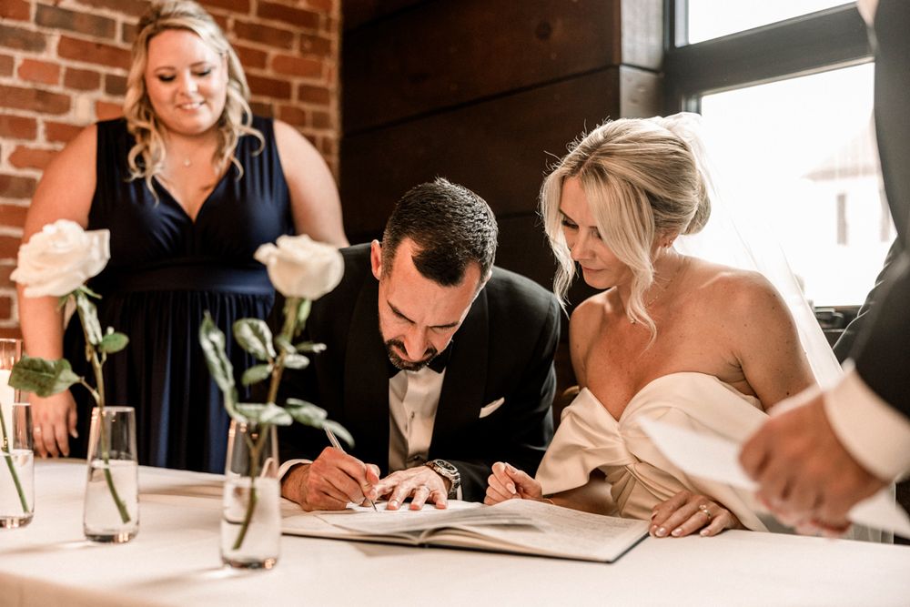 Bride and groom exchanging vows under wooden arch with greenery