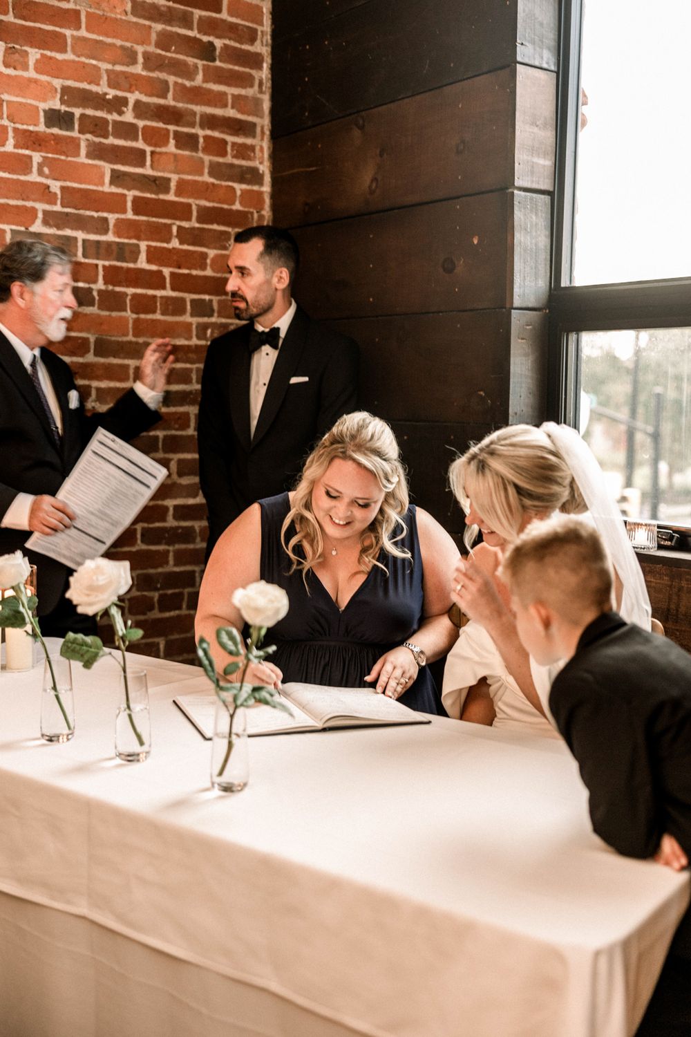 Bride and groom exchanging vows under wooden arch with greenery