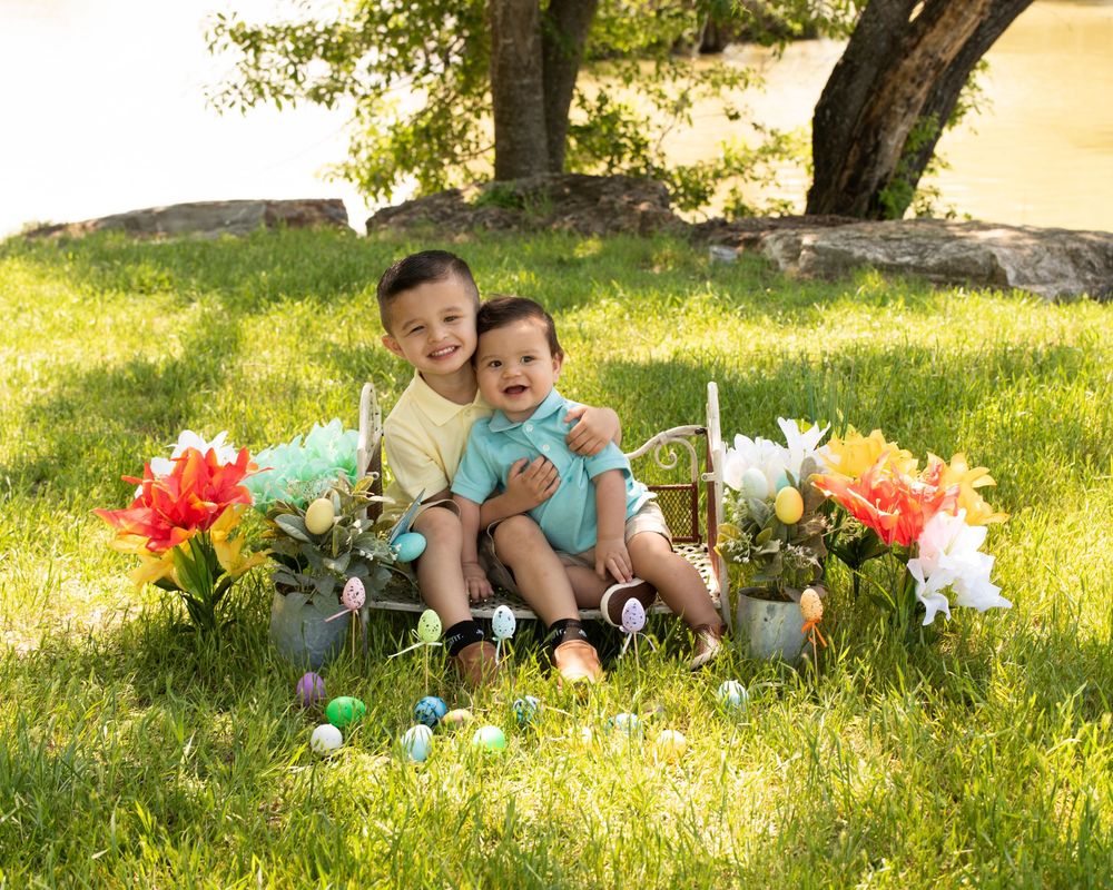 Children relax together in a sunlit garden surrounded by bright spring flowers and decorations.