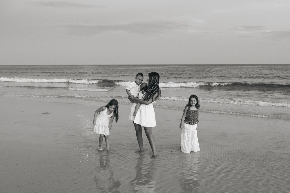 Black and white photographs show a series of beach scenes with people walking and playing along the shoreline.