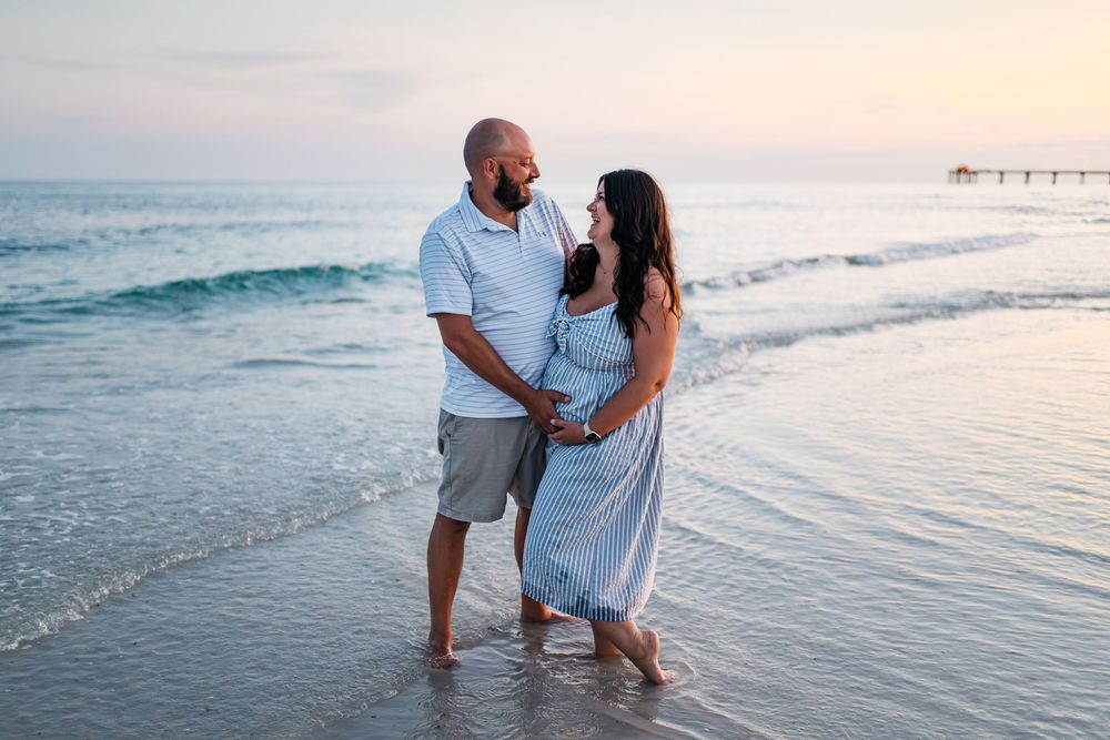 A couple shares romantic moments together walking and embracing on a sunlit beach during sunset.