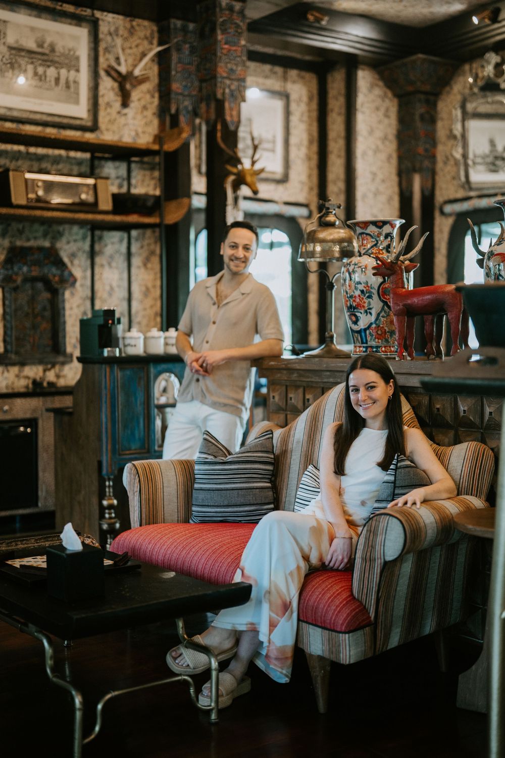 A couple enjoys a playful moment on vintage furniture in a rustic indoor setting.