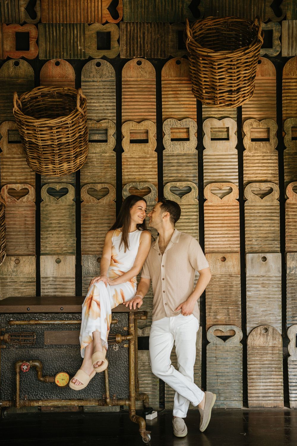 A couple poses against vintage wooden lockers in an industrial-style setting.