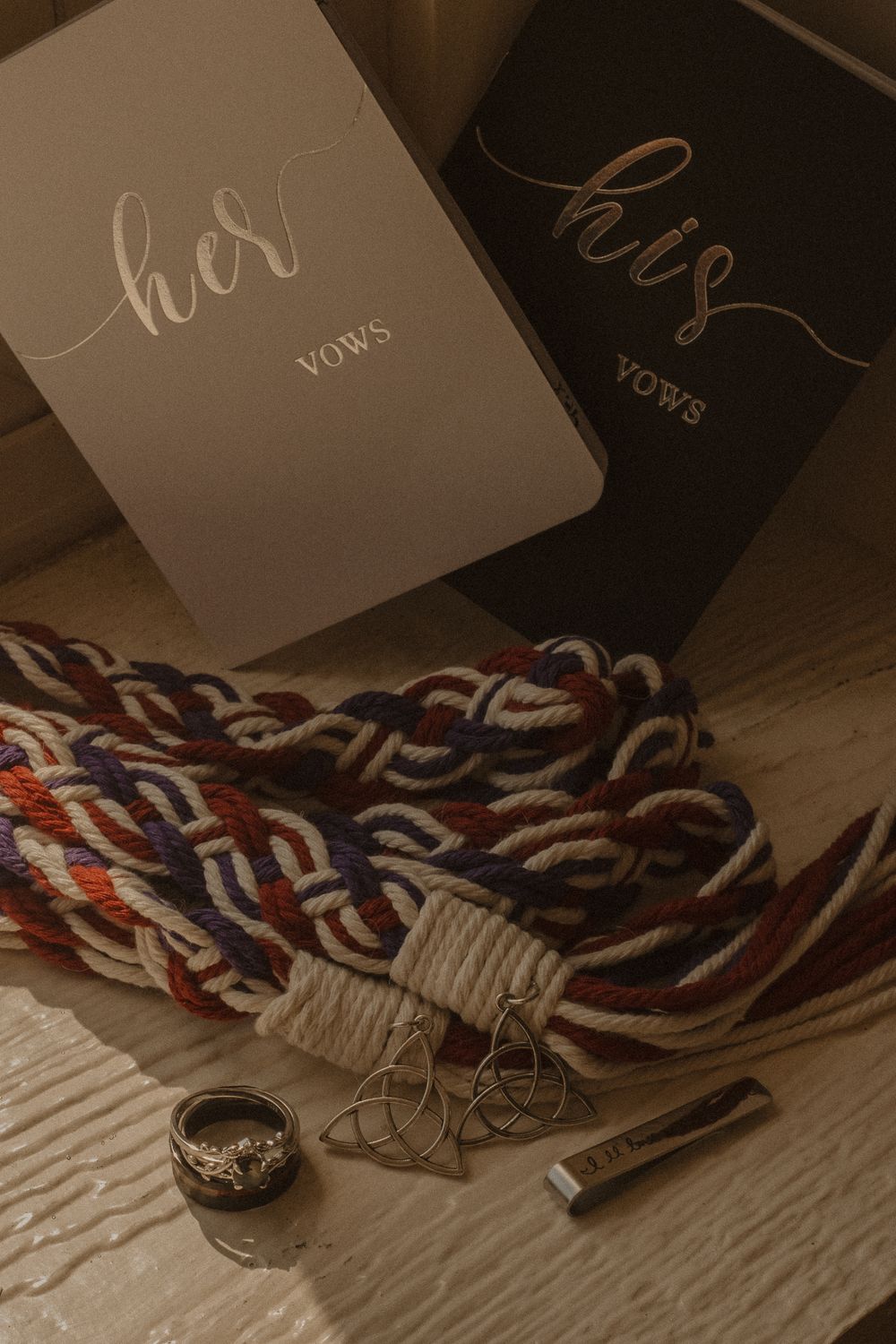Wedding accessories including rings and a decorative scarf arranged on a wooden surface.