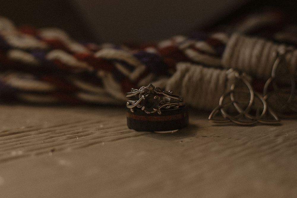 Wedding details including rings and accessories arranged artistically on a wooden surface.
