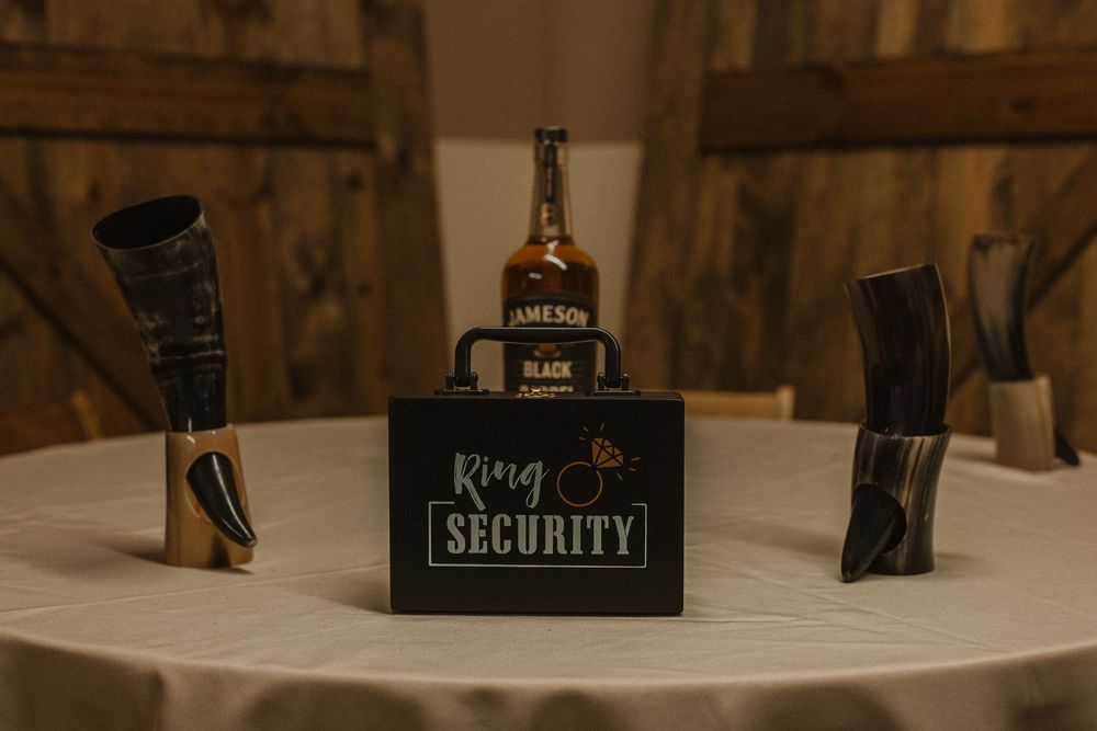 Wedding accessories including a security sign and ring box displayed on a wooden surface.