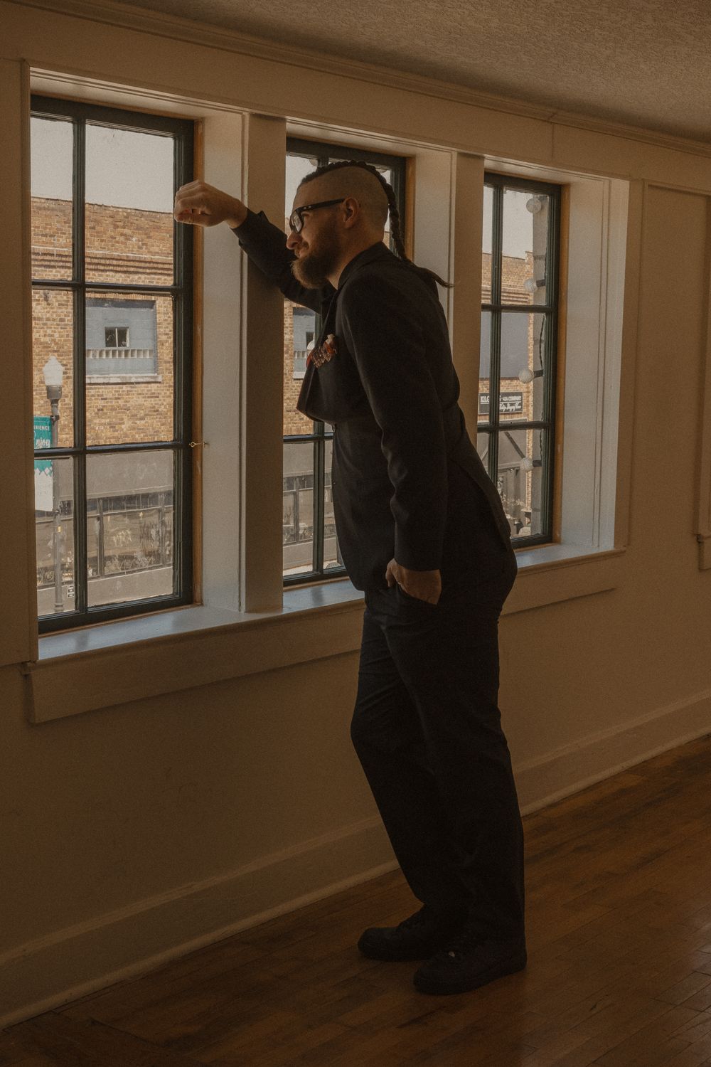 A security guard patrols a sunlit hallway with large windows.