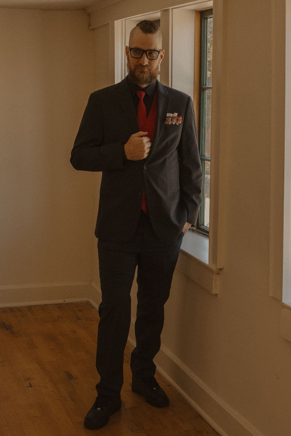 A security guard in formal attire stands in a bright hallway.