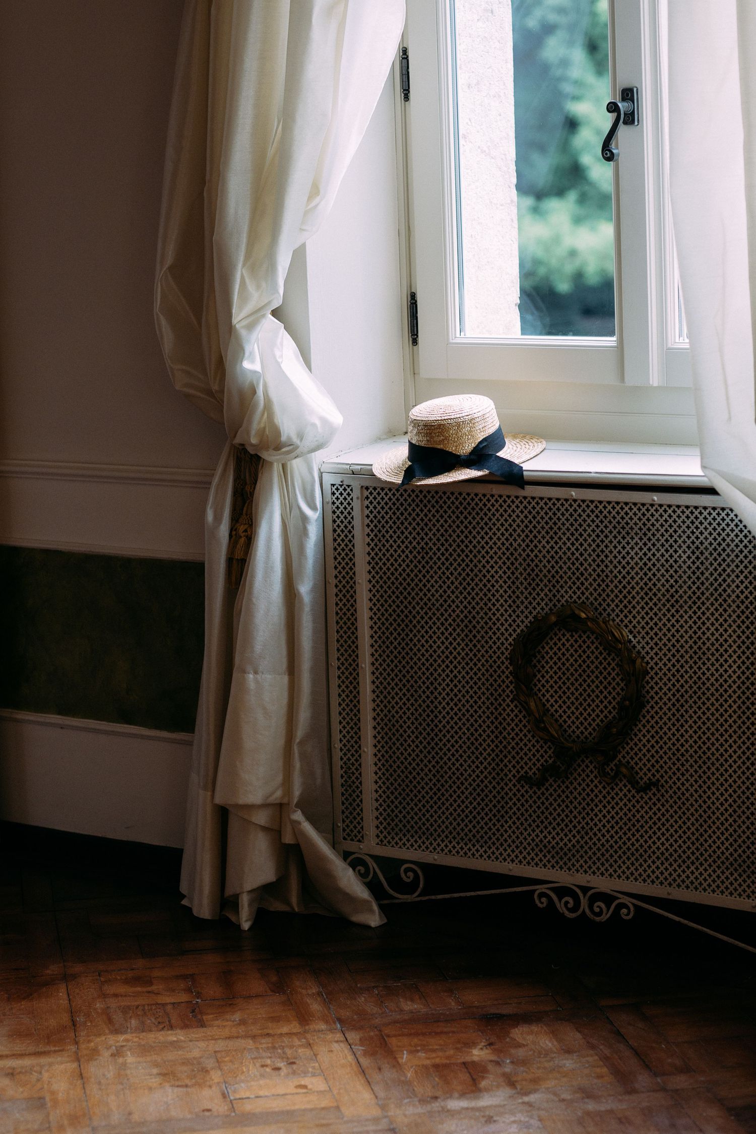 Soft natural light streams through white curtained windows in an elegant room with wooden floors.