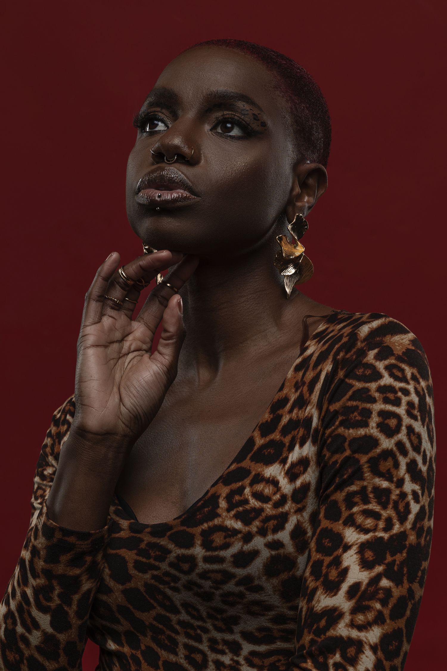 Fashion portrait series with leopard print top against deep burgundy background in dramatic lighting.