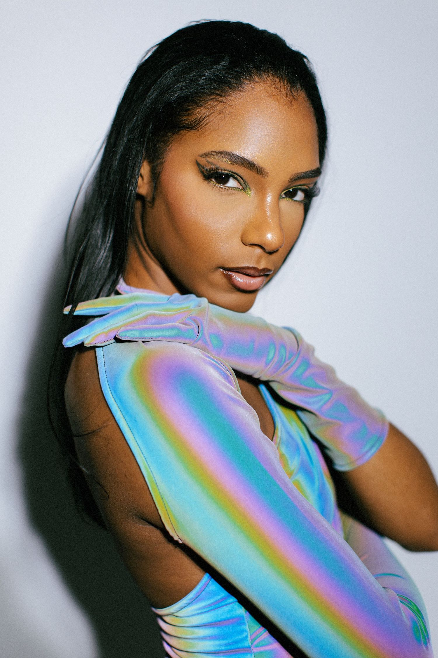 Fashion model wearing iridescent holographic gloves poses against white background in artistic portrait series.