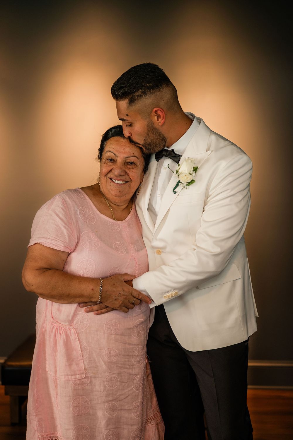 Sweet moment captured in a series of photos showing a tender embrace between two people in pink and white formal attire.