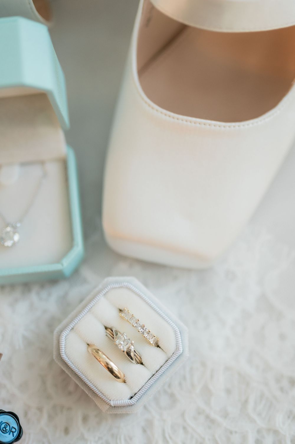 Delicate gold wedding rings nestled in a white velvet ring box with soft blue accents.