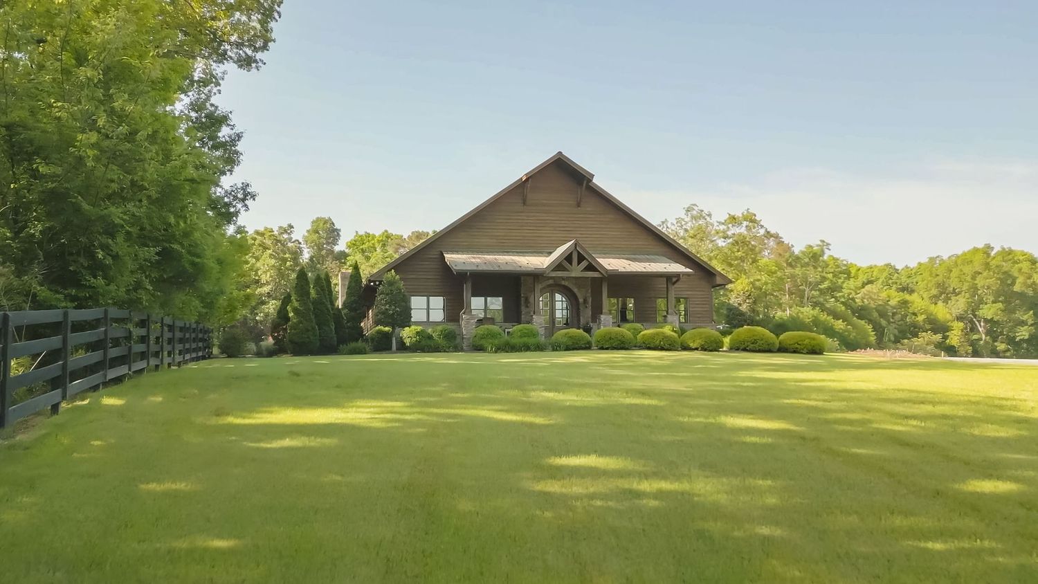 A scenic golf course landscape with rolling green fairways and trees stretches out under a bright blue sky.
