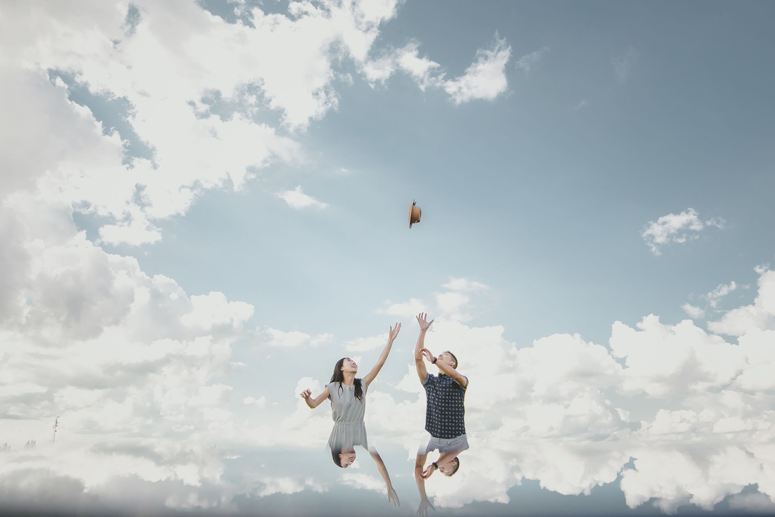 People perform backflips and acrobatic moves against a cloudy blue sky backdrop.
