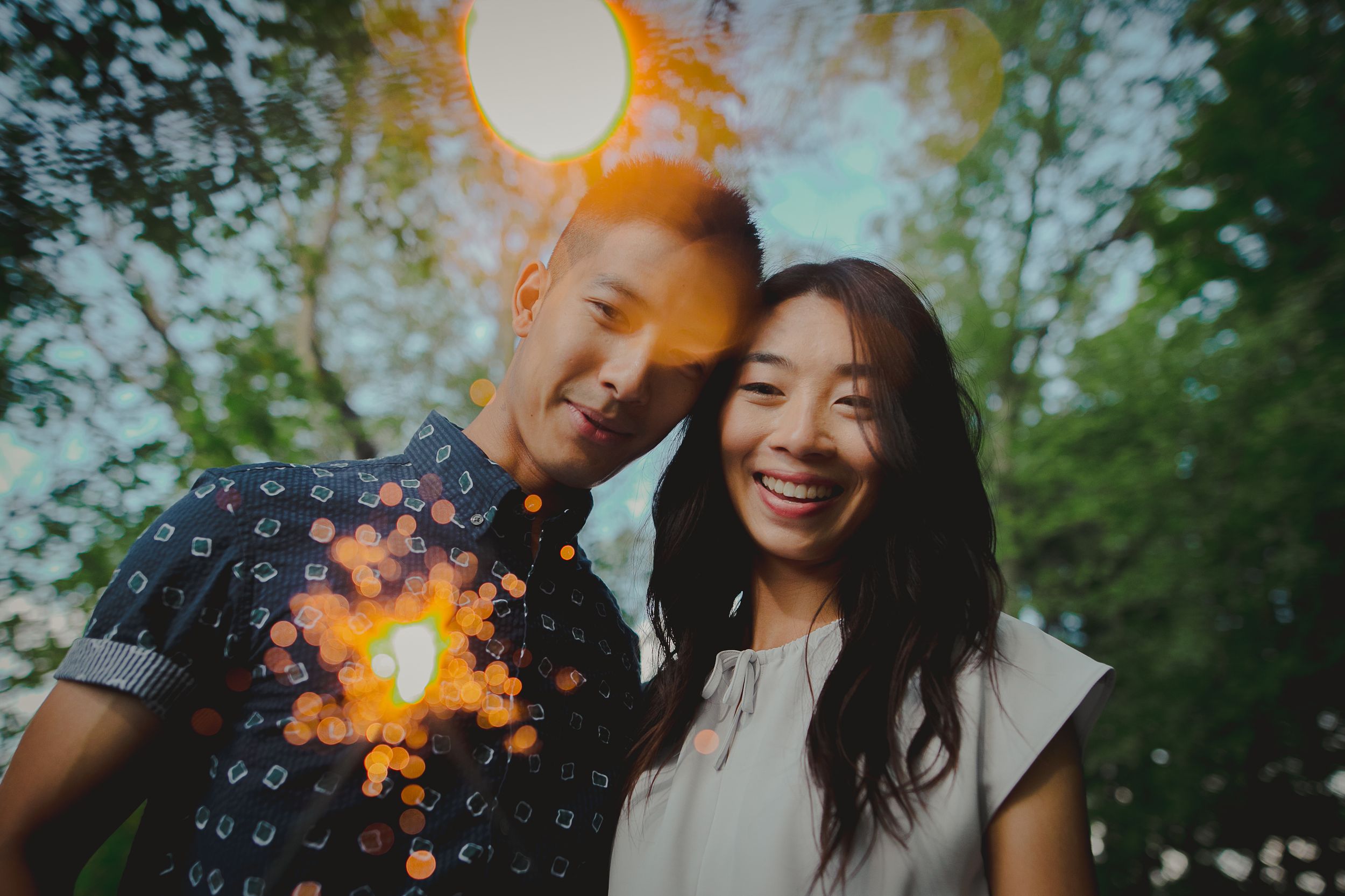 A couple poses outdoors with sparklers creating a magical glow in a romantic photoshoot.