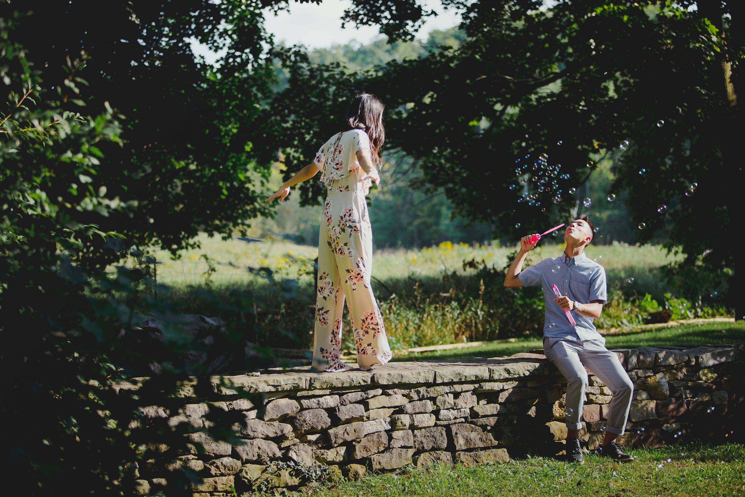 Couple walking together through a lush green garden path on a sunny summer day.