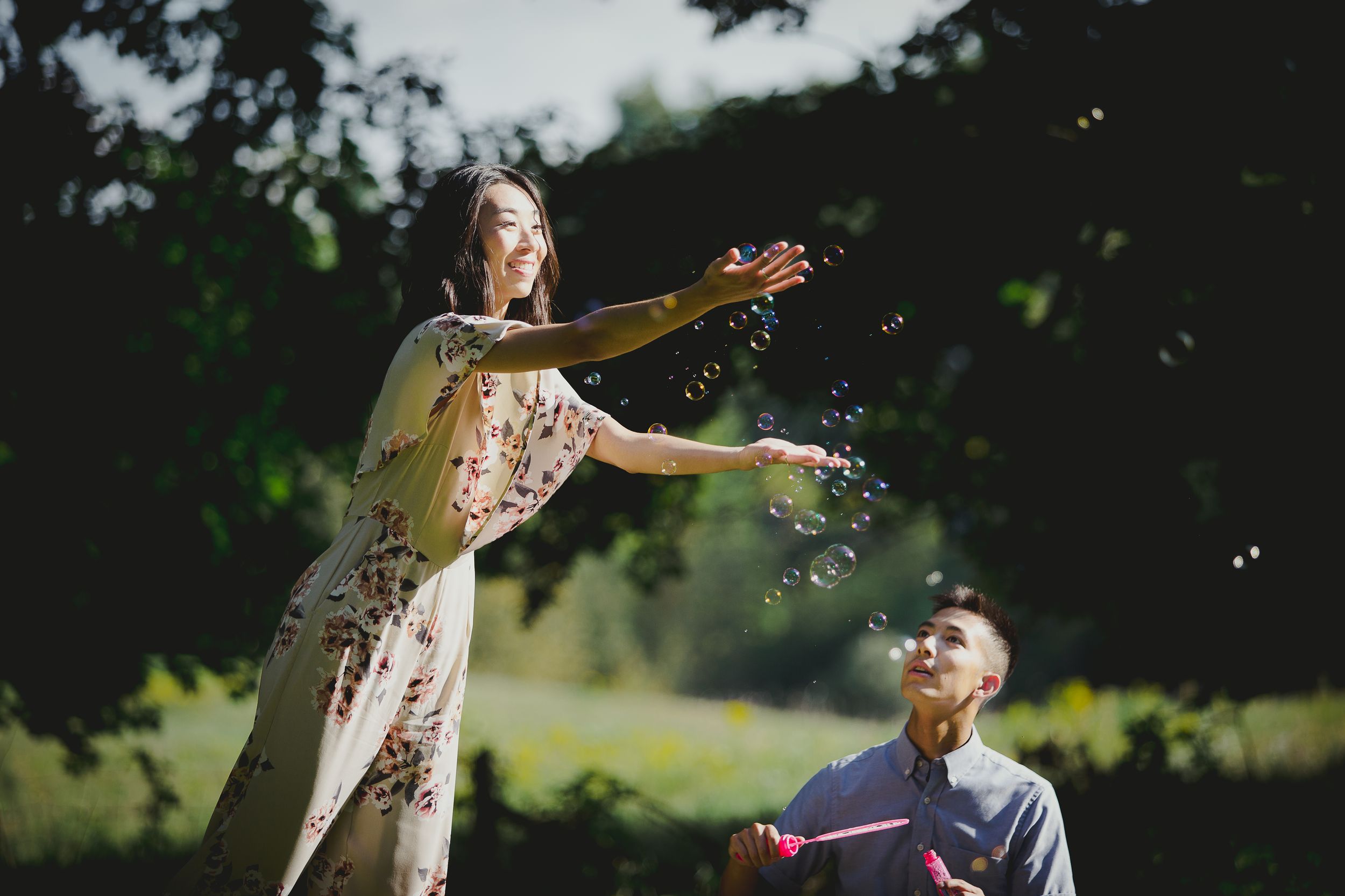 Two people playing and splashing water outdoors on a sunny summer day.
