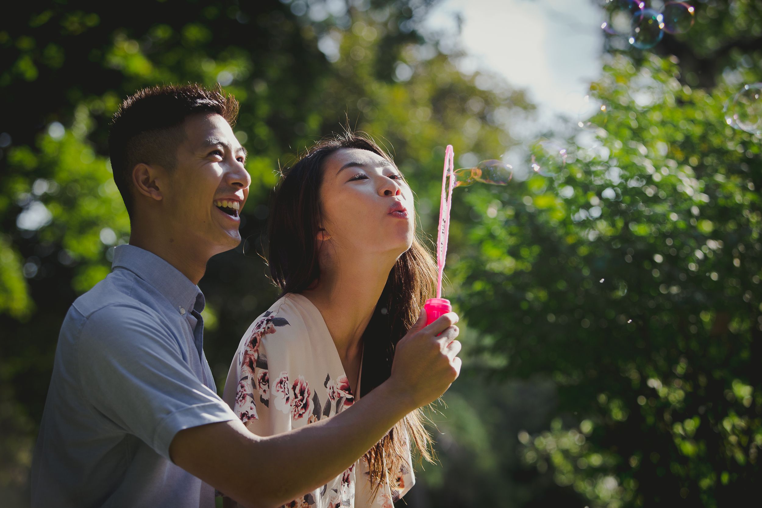 People blow bubbles together in a sunny garden setting during a summer day.