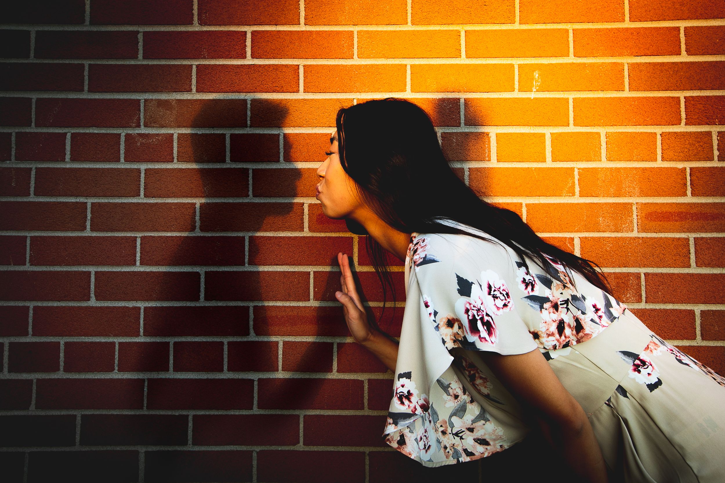 Dramatic orange lighting on brick wall creates intimate shadows and silhouettes.