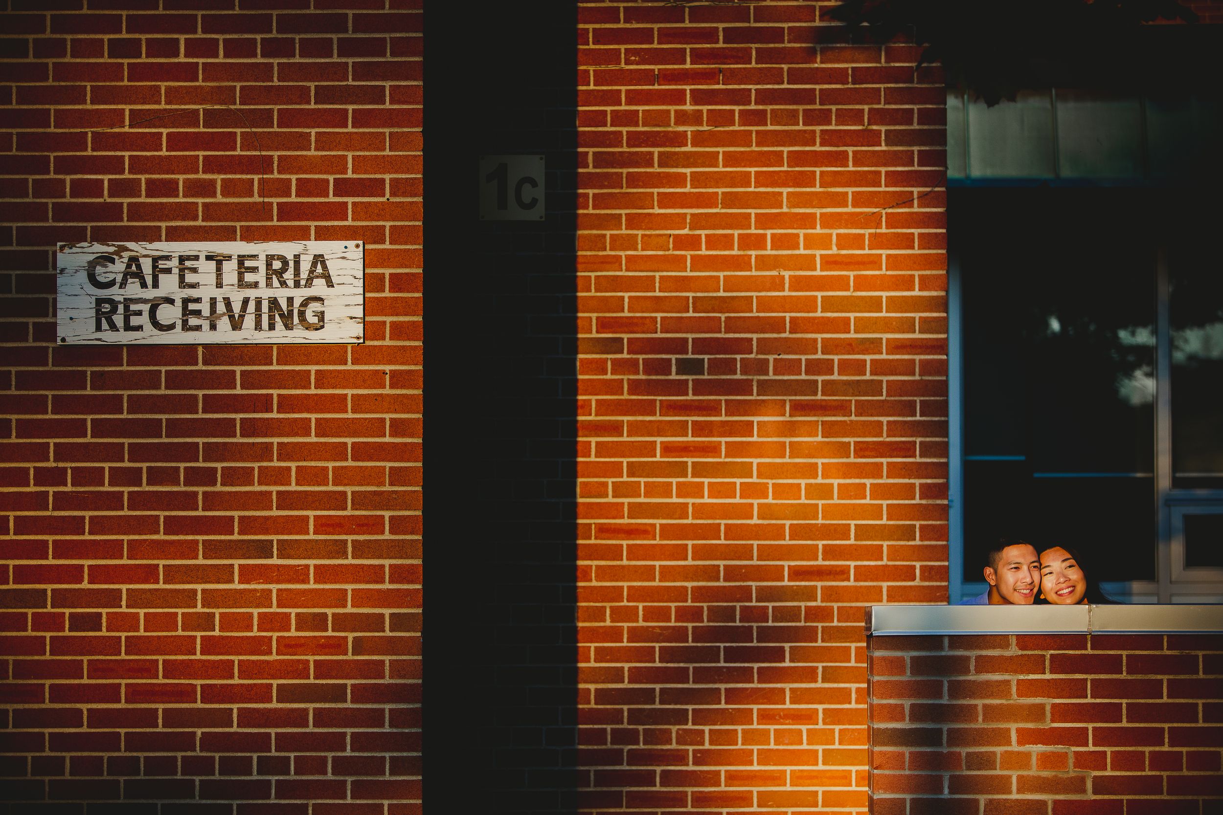 Brick wall of a cafeteria receiving area illuminated by warm sunset light through windows.