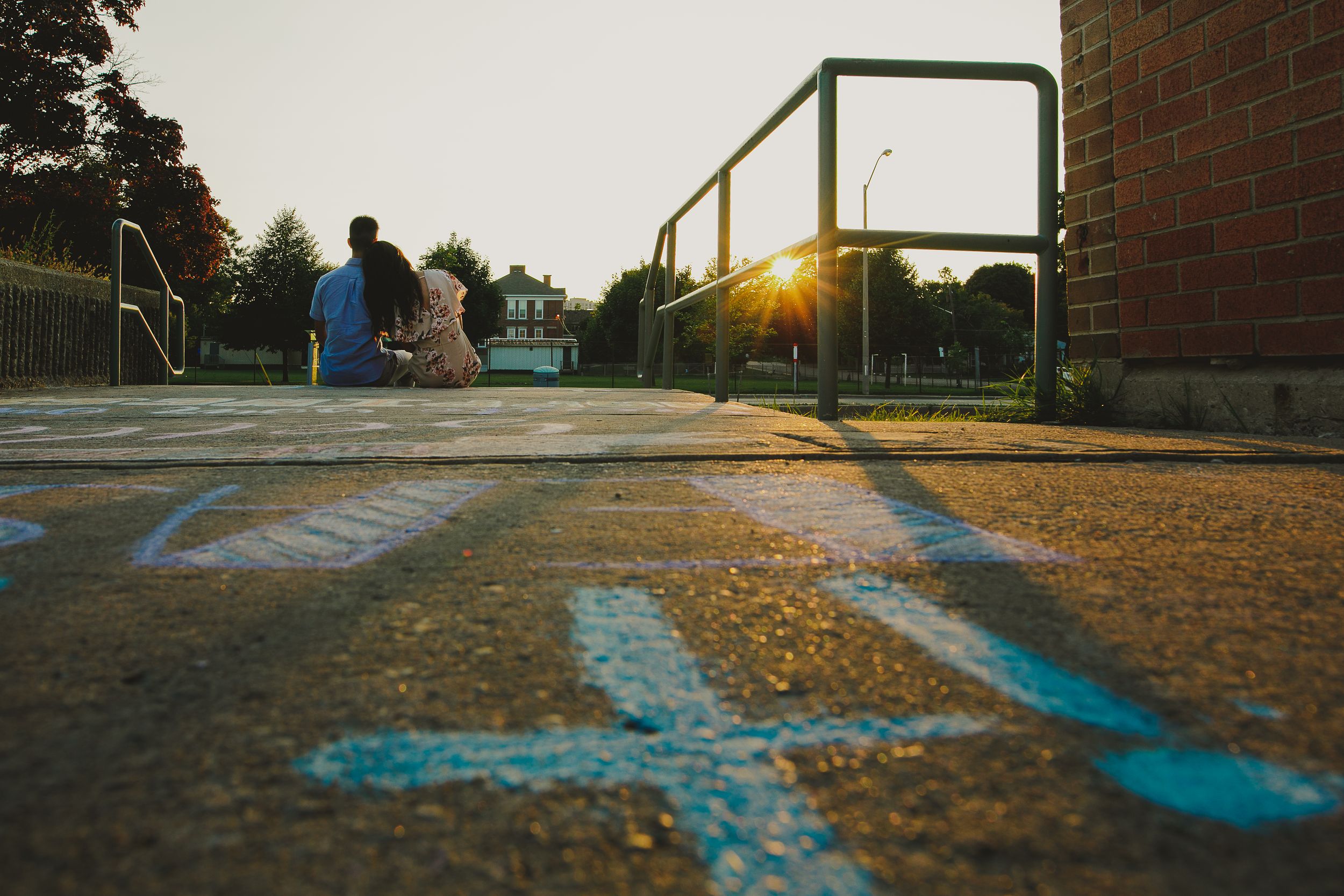Paved pathway with blue painted markings leads toward a brick building during golden hour sunset.