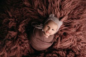 A brown shaggy carpet or rug texture closeup with swirling fibers and wool-like material creates an abstract pattern.