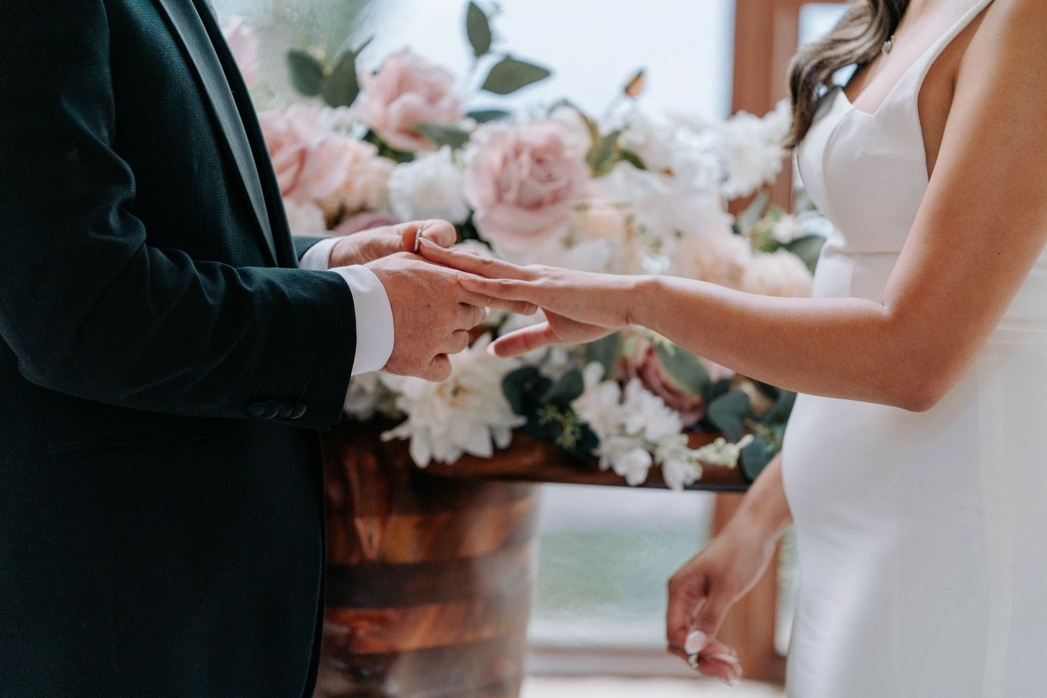 Wedding photographer captures candid moment between two people in elegant formalwear beside floral arrangements.