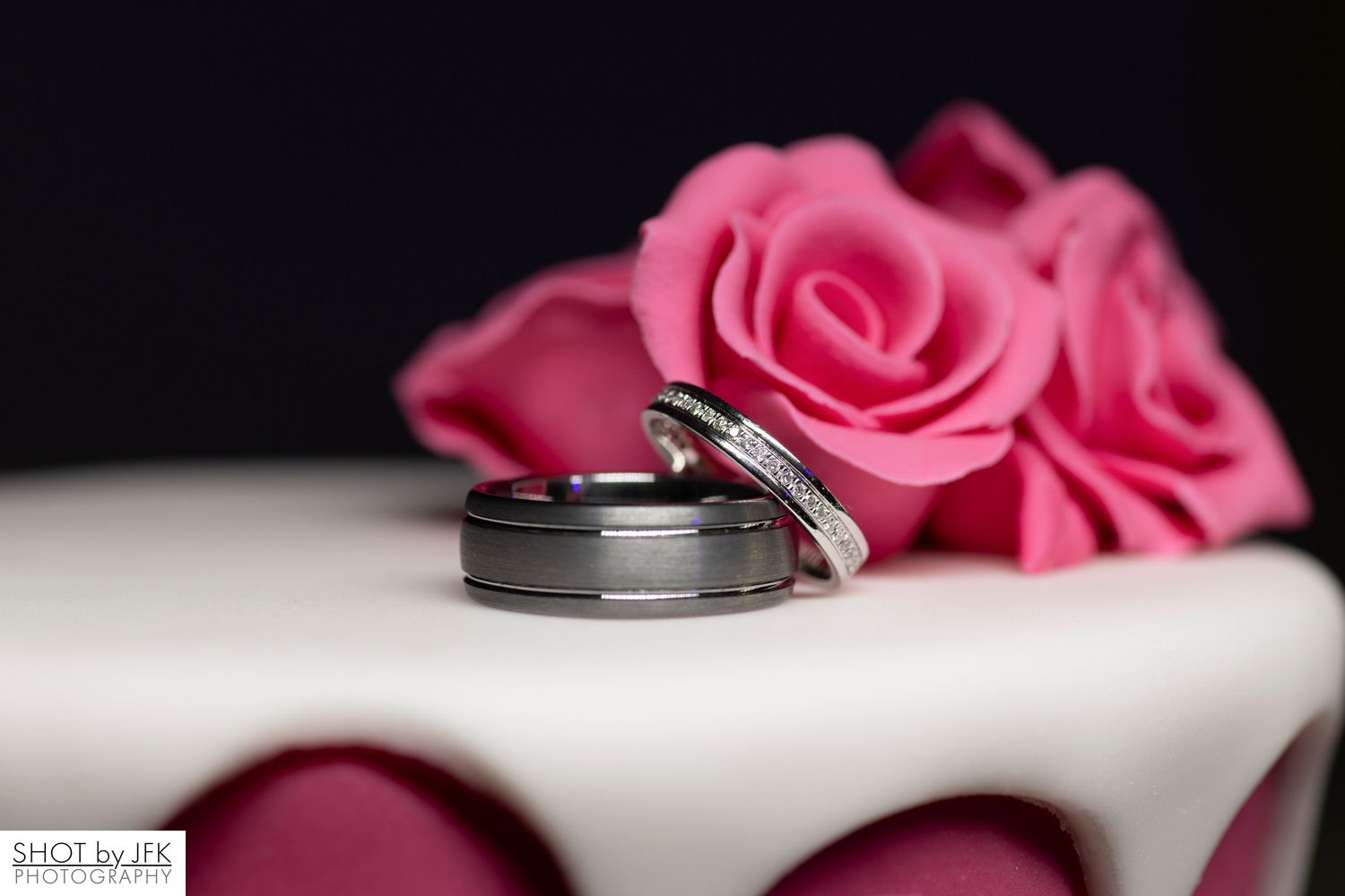 Wedding rings rest elegantly against pink roses swift a shallow depth of field creating a romantic composition.
